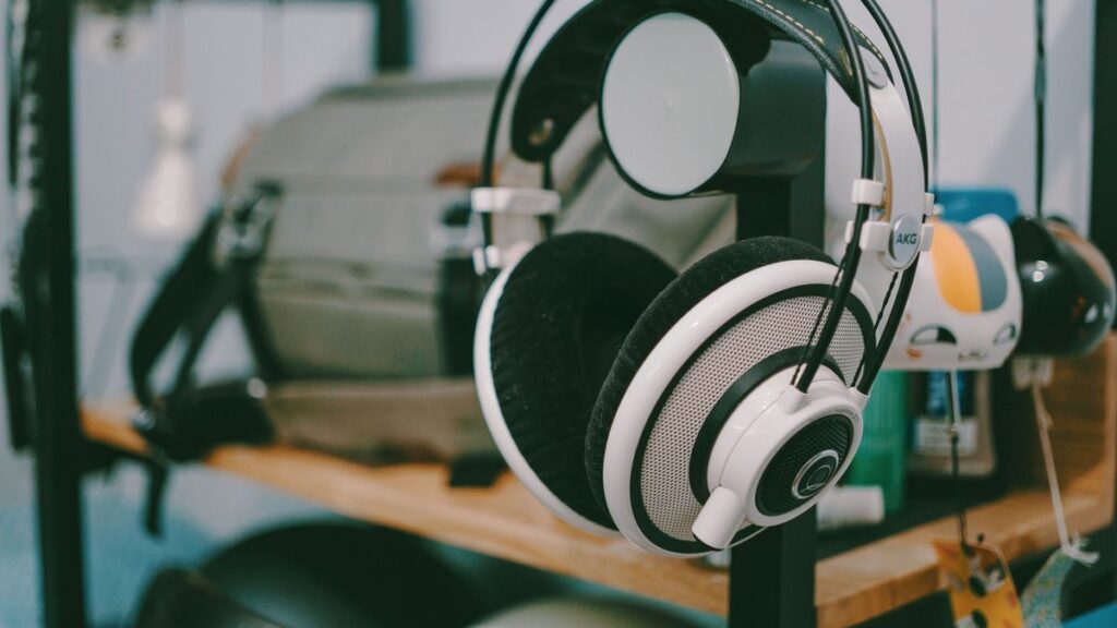 Close-up of AKG headphones hanging on a shelf in an indoor setting.