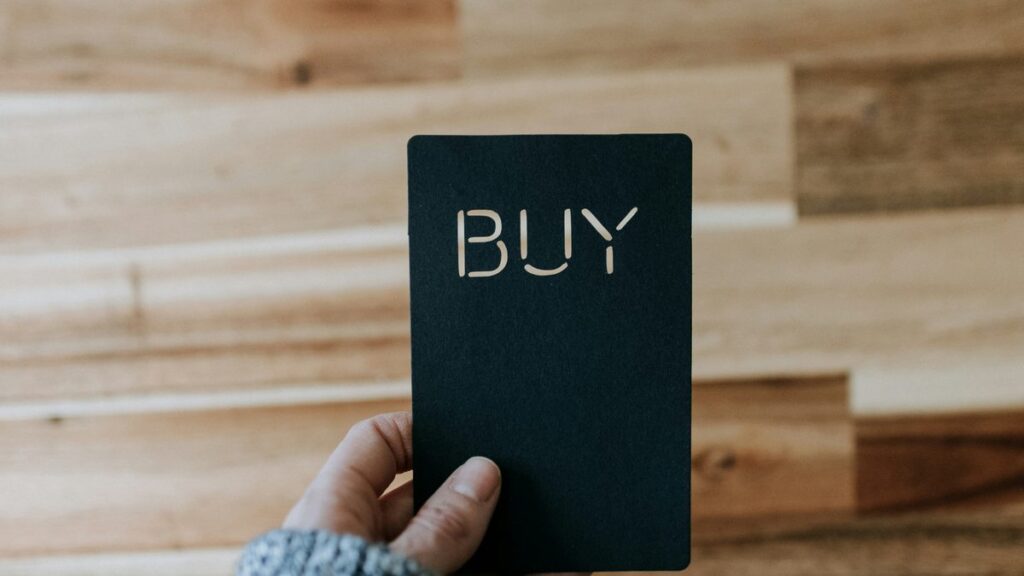 a person holding a black book with the word buy written on it