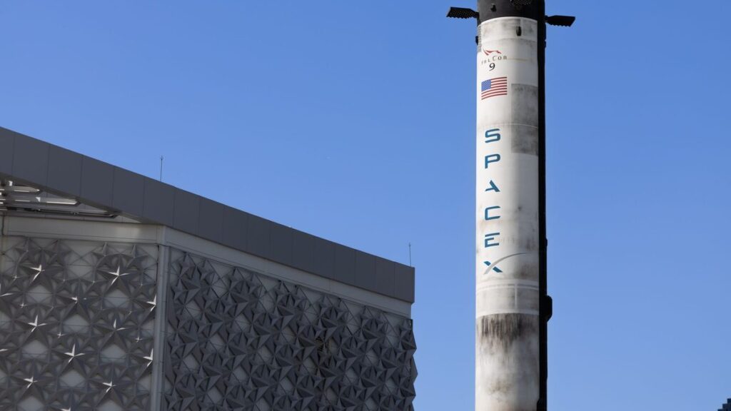 A SpaceX Falcon 9 rocket displayed outdoors against a clear blue sky in Dubai.