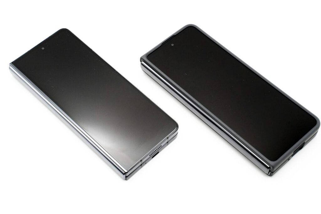 Two black Android smartphones lying side by side on a white surface with their screens off